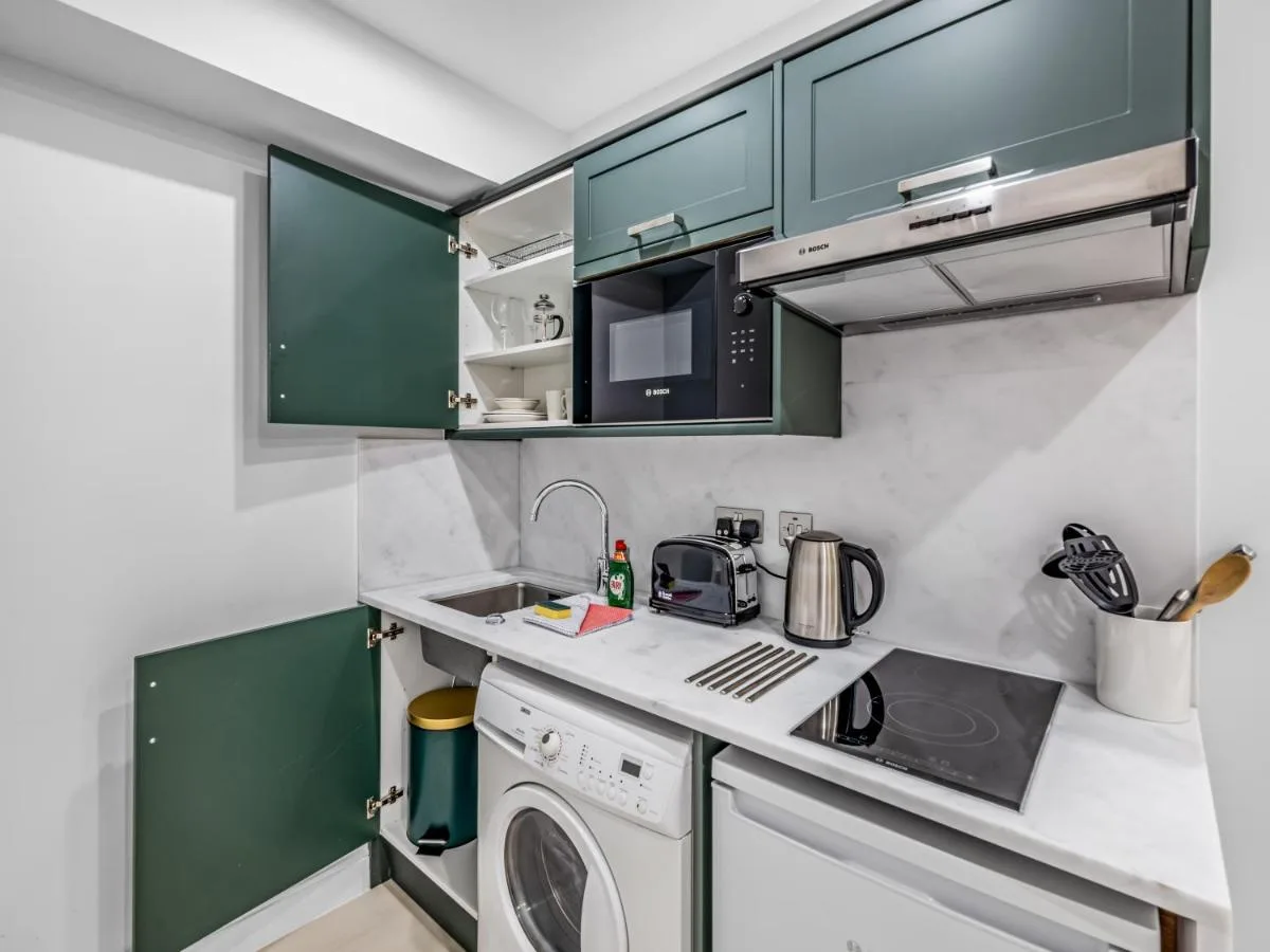Kitchen with green cabinets and washer-dryer at Chelsea Cloisters Serviced Apartments, Kensington and Chelsea